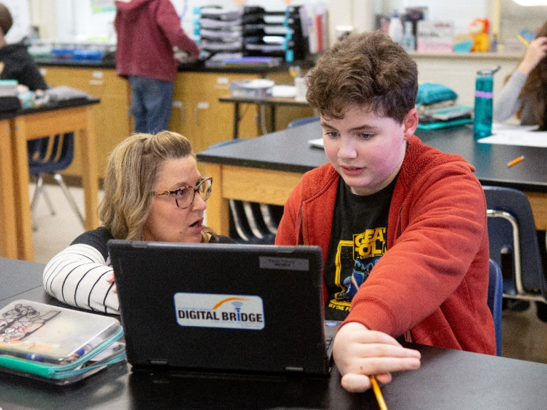 Female science teacher helps male student with assignment