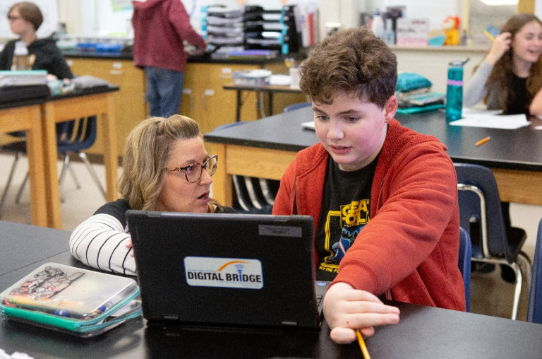 Female science teacher helps male student with assignment